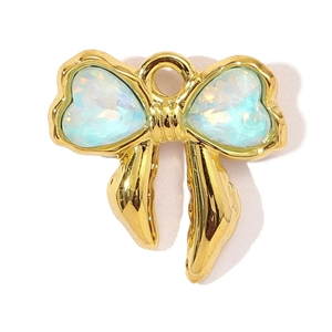 Macro shot of gold bow pendant with heart-shaped opal stones and polished metal frame