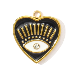 Macro view of a gold heart charm with black enamel, eye motif, and crystal inlay