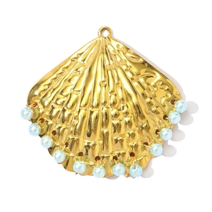Detail van een schelpvormige gouden hanger met lichtblauwe parels en textuur