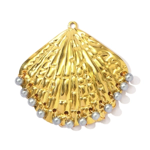 Detailopname van een gouden schelphanger met grijze parels en metalen oppervlakte