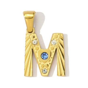 Detailaufnahme eines goldenen M-Anhängers mit blauem Edelstein und Kristallen