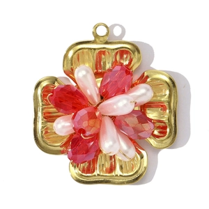 Detailed view of a gold-plated flower cross pendant with red crystals and white beads