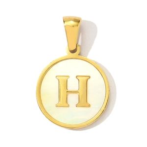 Macro detail of round gold pendant with white shell inlay and gold letter H charm