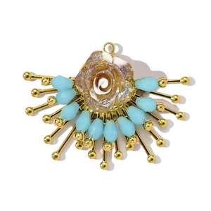 Vue détaillée du pendentif fleur fait main avec rose en résine dorée et perles bleues