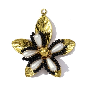 Detailopname van een vergulde bloemhanger met witte parels en zwarte kralen versiering