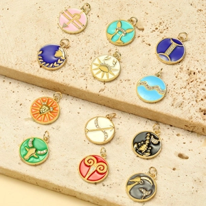 Set of 12 zodiac enamel charms in gold plating with rhinestones on stone background
