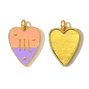 Detail of heart zodiac charm with pink enamel and gold plated m symbol on white background