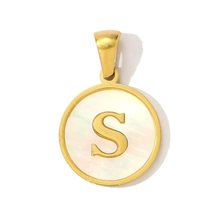 Detailed macro view of a round gold pendant with white mother of pearl and letter S inlay