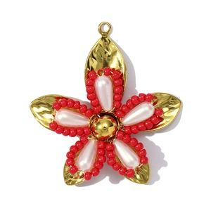Detail van een vergulde bloemhanger met rode kralenranden en witte parelachtige bladen
