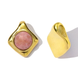Dettaglio di pendenti in acciaio dorato con pietra naturale rosa sfaccettata