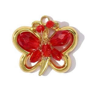 Detailed close-up of a gold butterfly pendant with faceted red crystal beads and wire work