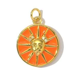 Macro shot of gold-plated sun medallion charm with orange enamel and crystal details