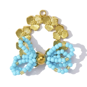 Macro detail of gold flower wreath and light blue beaded bow pendant with metal texture
