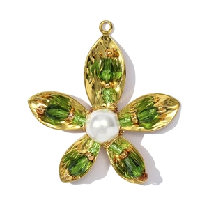 Detailweergave van gouden bloemhanger met groene kristallen kralen en een parel