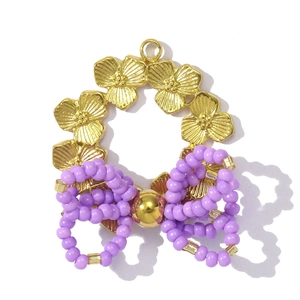 Detailed macro of gold flower pendant with purple beaded bow and stainless steel ring