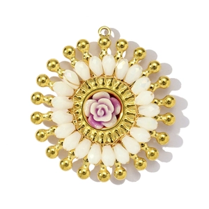 Détail d'un pendentif fait main avec rose rose, perles de cristal et bordure dorée