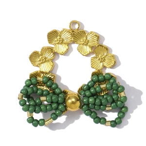 Detail of a floral gold pendant with a green beaded bow and fine metal textures