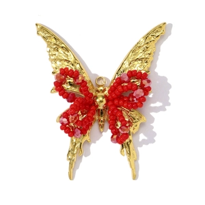 Detailweergave van een gouden vlinderhanger met rode facetgeslepen kristallen kralen