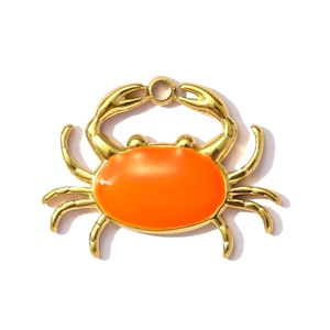 Detailopname van een goudkleurige krab hanger met oranje emaille en een ronde ophangring