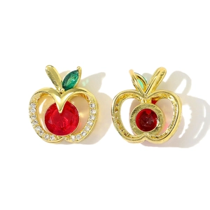 Dettaglio di orecchini a mela in oro con pietra rossa e foglie di zircone verde