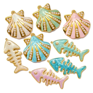 Macro detail of enamel fishbone and shell charms with pearls for DIY jewelry making