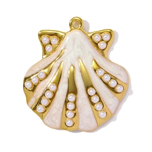 Detailed macro view of a gold-plated shell pendant with white enamel and pearl accents