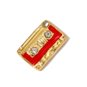 Detalle de un colgante de casete dorado vintage con esmalte rojo y diamantes de imitación