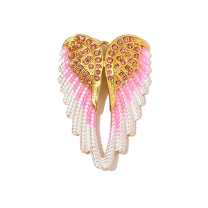 Detailed view of large angel wing pendant with pink rhinestones and enamel on gold base