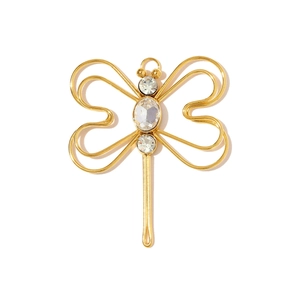 Macro detail of a golden dragonfly pendant featuring three clear sparkling zircons