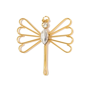 Macro detail of a gold dragonfly pendant with sparkling rhinestones and hollow wing design