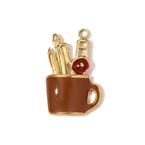 Detail of an enamel teapot charm with golden pens and a red flower on a white background