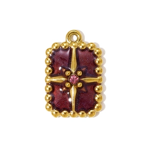 Macro detail of a rectangular gold-plated pendant with burgundy enamel and pink crystal