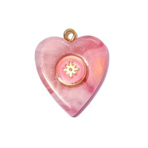 Close-up of pink resin heart pendant with gold star emblem and sparkling glitter