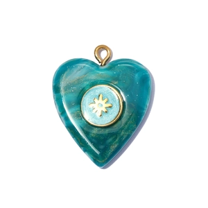 Detail of heart-shaped resin pendant with marble texture and golden starburst center