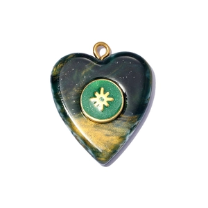 Macro detail of heart-shaped stainless steel pendant with green resin nebula texture