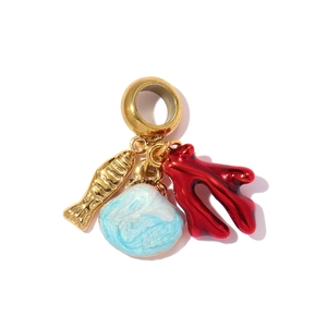 Detailed view of nautical charms featuring a gold fish, blue shell, and red coral branch