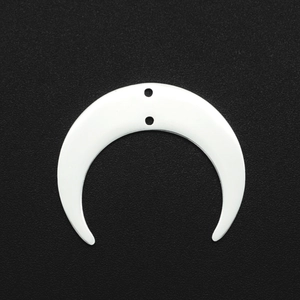 Close-up of crescent-shaped white shell pendant with two holes on black background