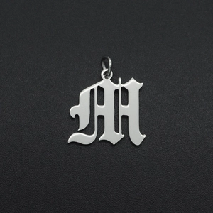 Detailweergave van een zilveren M-letter hanger van roestvrij staal in gotische stijl