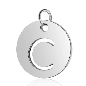 Détail macro d'un pendentif rond en acier inoxydable poli avec la lettre C ajourée