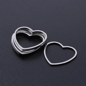 Macro shot of silver heart-shaped stainless steel DIY pendants on a textured black base