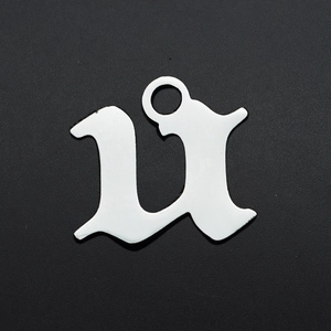 Makroansicht eines silbernen Edelstahl-Gothic-Buchstaben-U-Anhängers auf schwarzem Grund