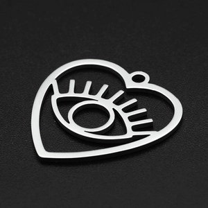 Detailed view of heart-shaped evil eye pendant with eyelashes in polished stainless steel