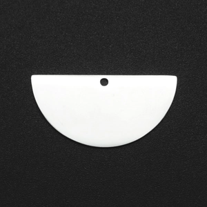 Macro shot of white semi-circular acrylic jewelry pendant with single hanging hole