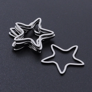 Macro shot of silver polished stainless steel star-shaped DIY jewelry charms on black surface