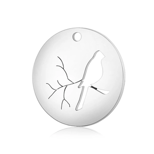 Detailed view of a round stainless steel pendant with bird on branch cutout design