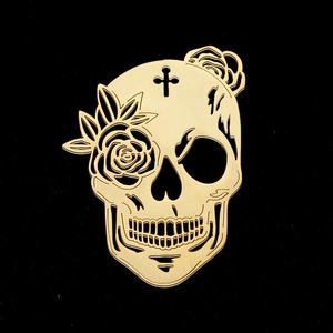 Detailed macro shot of golden stainless steel skull pendant with rose and cross engraving
