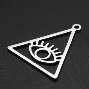 Macro shot of silver stainless steel triangle evil eye pendant with intricate hollow design