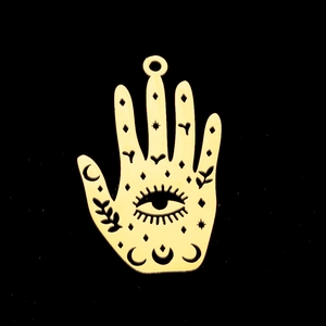 Macro shot of gold hamsa hand pendant featuring moon, stars, and botanical cutouts