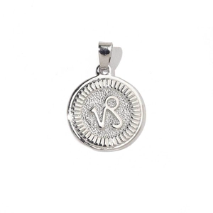 Macro shot of silver Capricorn zodiac coin charm with engraved constellation symbol