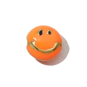 Macro view of orange enamel smiley face pendant with gold stainless steel details